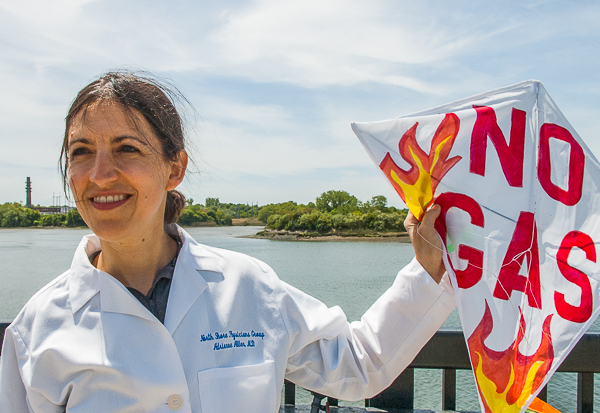 Woman in white coat holding kite "No Gas"