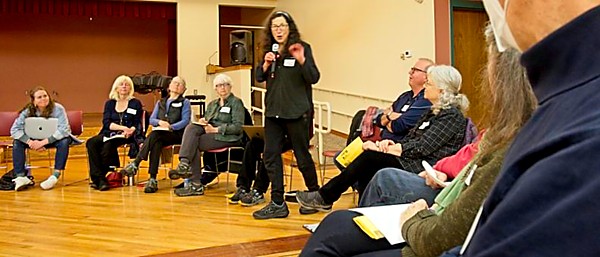 Woman stands to address seated people