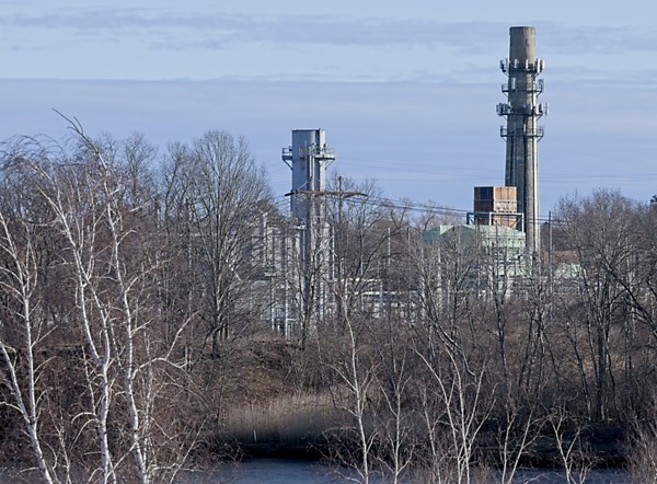 river with wetlands and industrial buildings with smokestacks